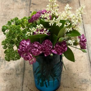 purple carnations white lilacs and green parsley in a blue glass.