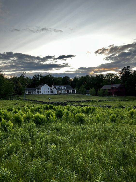 a beautiful white farm with a red barn on a green field. 