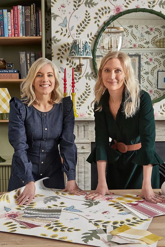 Two home standing over a table filled with fabric swatches. 