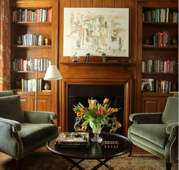 two green velvet chairs in a wood paneled library
