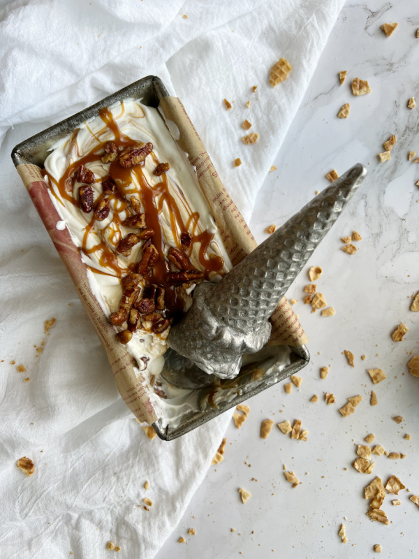 Salted Caramel Candied Pecan No Churn Ice Cream in a loaf pan with an ice cream shaped Ince cream scoop in it. 