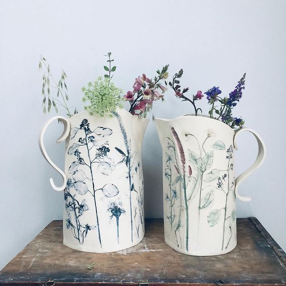 two clay pitchers with pressed flower inlay. 