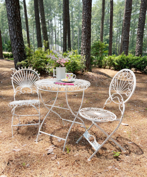 tea and a book with a vase of wildflowers set on vintage white garden furniture