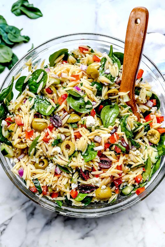 Mediterranean Orzo Salad in a bowl with a wood serving spoon. 