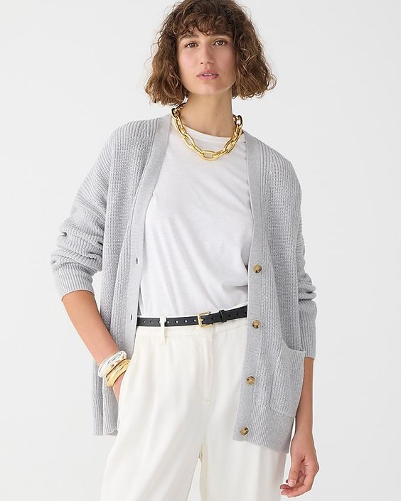 Woman wearing white pants, white t-shirt and a gray cardigan sweater. 