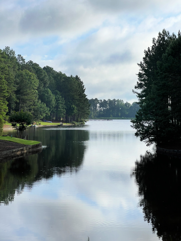 A lake with pine trees on both sides reflecting in the water. 