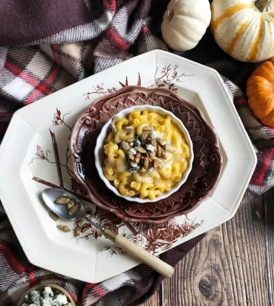 Pumpkin-Mac-and-Cheese-on-a-transferware plate sitting on plaid-blanket