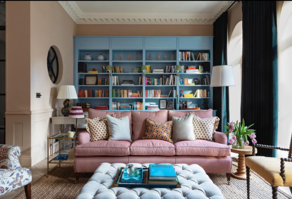 Colorful English sitting room with blue bookcases and a red couch. 