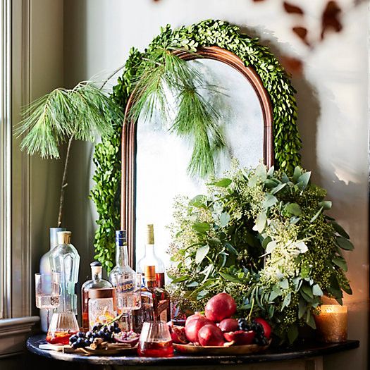 A mirror decorated for Christmas with garland and a wreath.