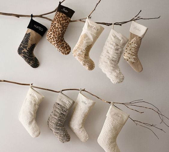 9 christmas stockings hanging on a branch. 