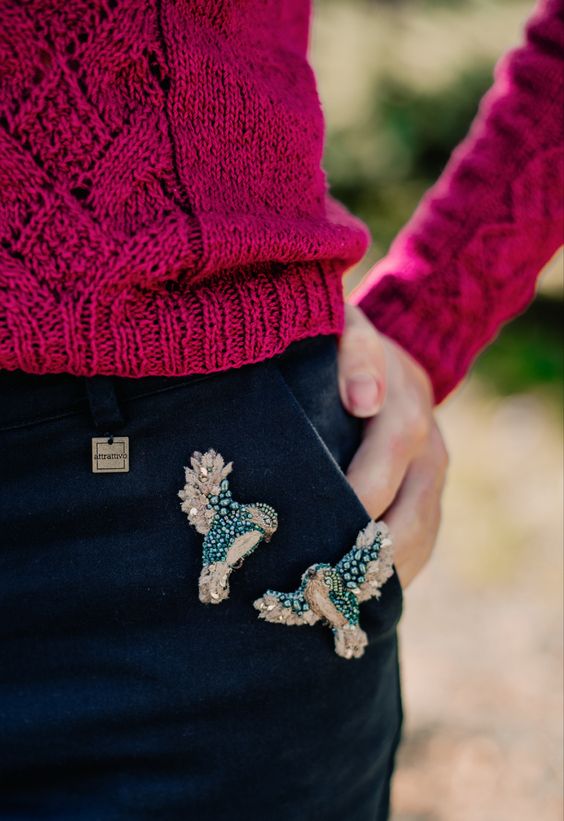 Two bird brooches on a pants pocket. 