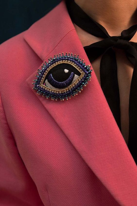 Eye brooch on a pink lapel. 