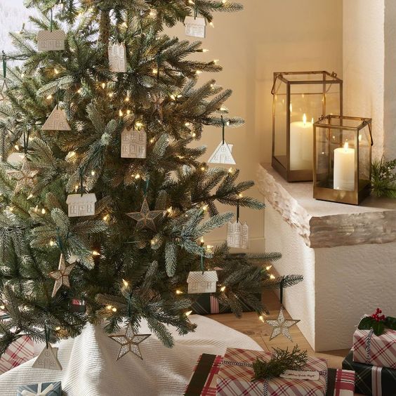 A Christmas tree with white ornaments and 2 glass lanterns. 