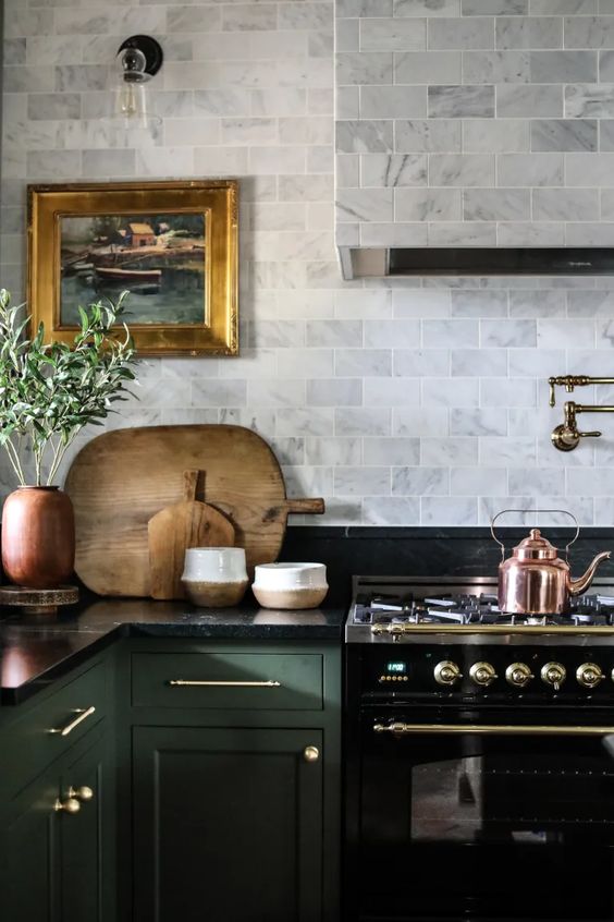 A kitchen with dark green cabinets, black stove and marble cabinets. 