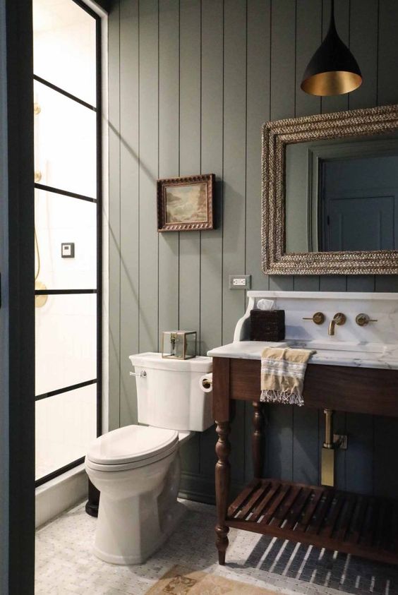 A pale green ship lap bathroom with marble sing and wood vanity. 