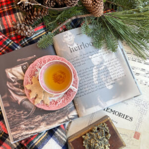 Flatlay with evergreen a cup of tea and cookies and a book.