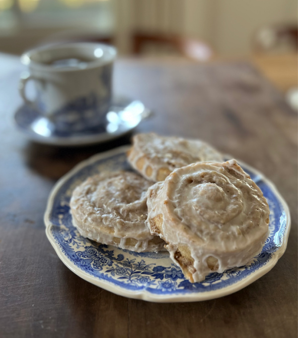 Three German Nut Rolls Nussschnecken on a blue and white plate with a cup of tea. 