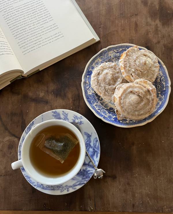 German Nut Rolls Nussschnecken on a blue and white plate with a cup of tea and an open book.