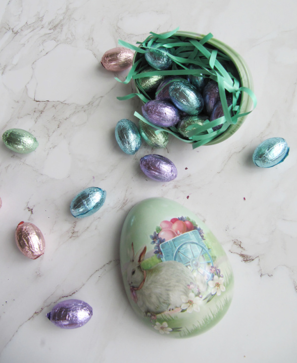 Vintage aluminum Easter egg with a bunny filled with green grass and pastel colored chocolate eggs.