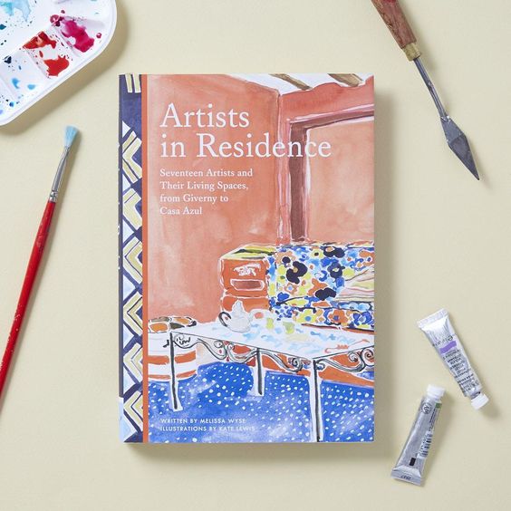 Kate Lewis, Artists in Residence book with tubes of watercolor paint, paintbrushes and a water color palette. 