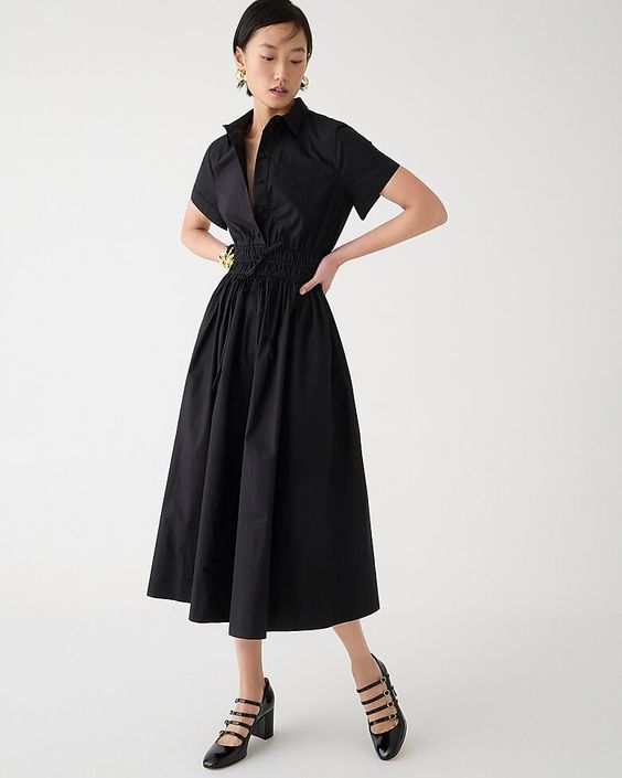 Woman wearing black heels and a black shirtdress. 