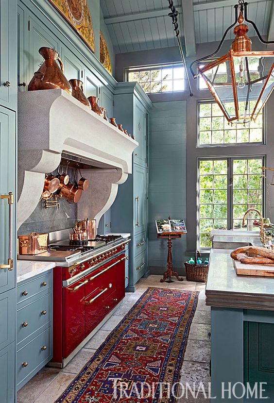 A blue kitchen with a red stove. 