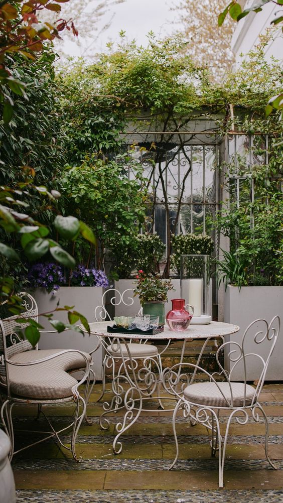 A white set of iron garden furniture in a walled English garden 