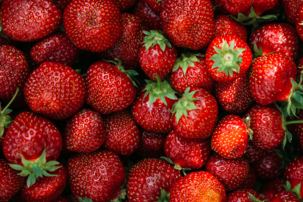 a pile of fresh red strawberries with bright green stems. 