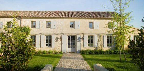 Maison Dubreuil, French Country house made of cream colored stone with pale blue shutters. 