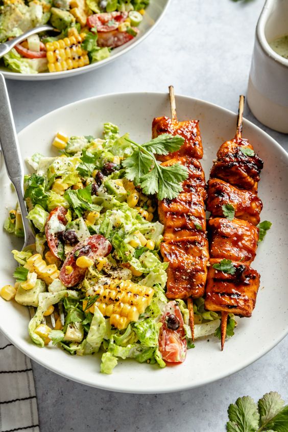 bbq chicken skewer salad with corn and lettuce. 