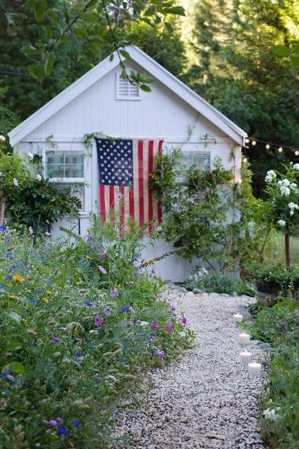 American flag on a white shed in a wildflower garden