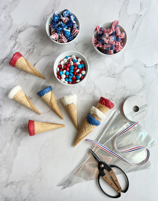 Cones and candy with cellophane bags red white and blue ribbon and scissors.