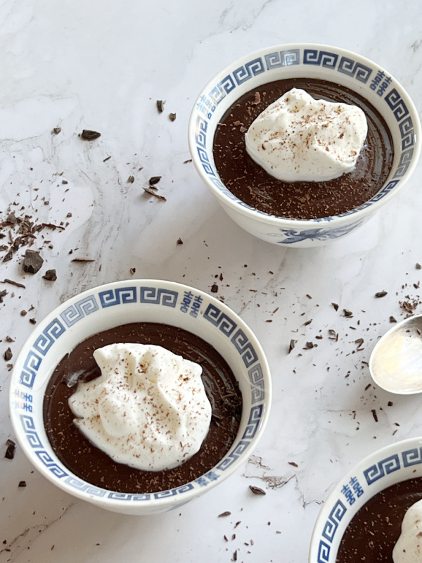 homemade chocolate pudding with whipped cream and chocolate shavings.