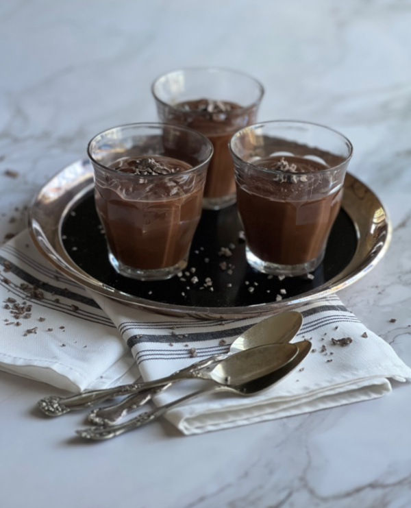 Three small glasses of Mocha chocolate pudding on a silver tray with spoons.