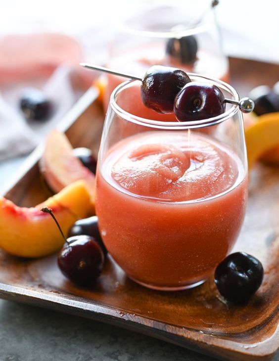 Frost wine in a glass with fresh cherry and peach slice garnish. 