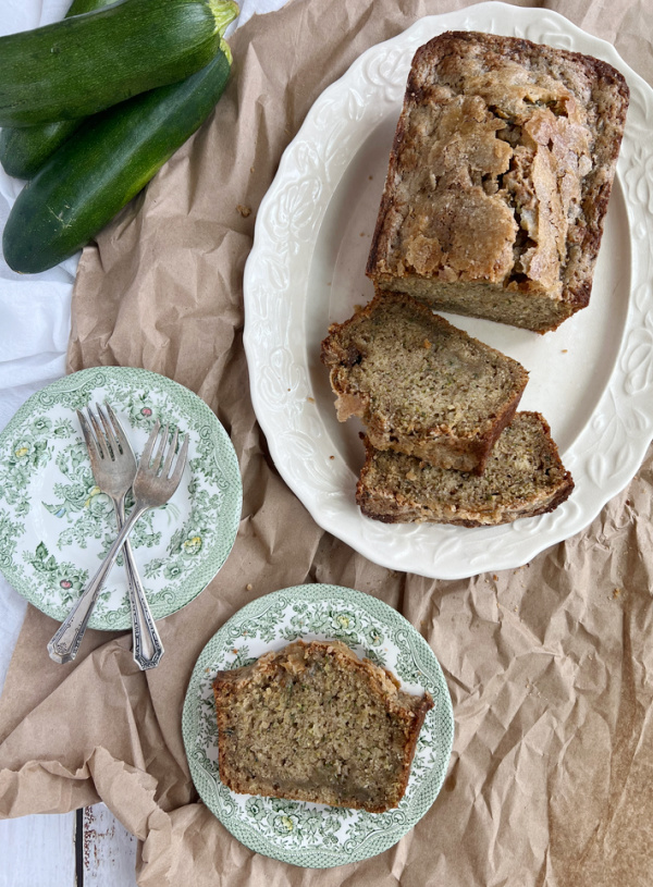 sliced zucchini bread on a vintage ironstone platter with 2 green and white transfer ware plates.