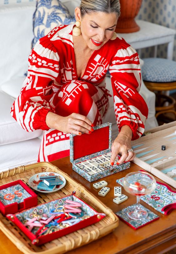 Pencil & Paper for Marks and Graham woman in red and white dress playing with a colorful box of dominos. 