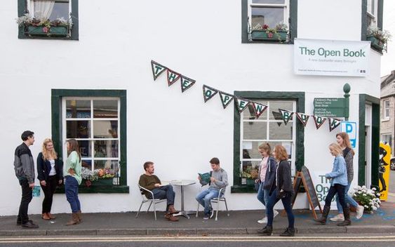 The Open Book Airbnb, white building with green bunting and people milling about. 