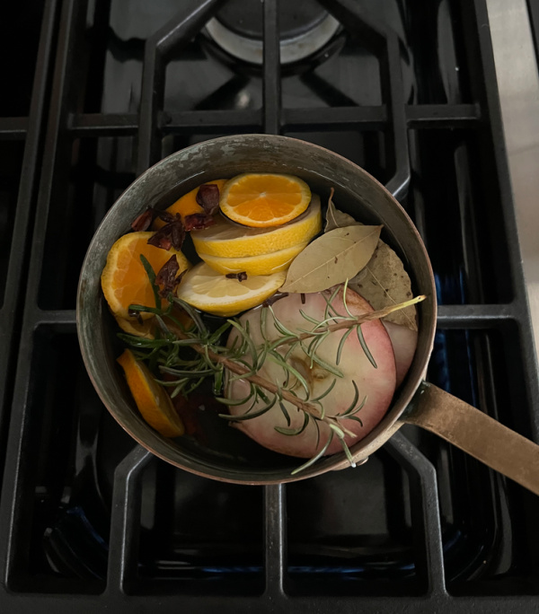 copper fall simmer pot on stove with oranges, limes, apples and bay leaves.