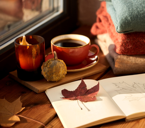 cup of coffee, journal, and a pile of sweaters
