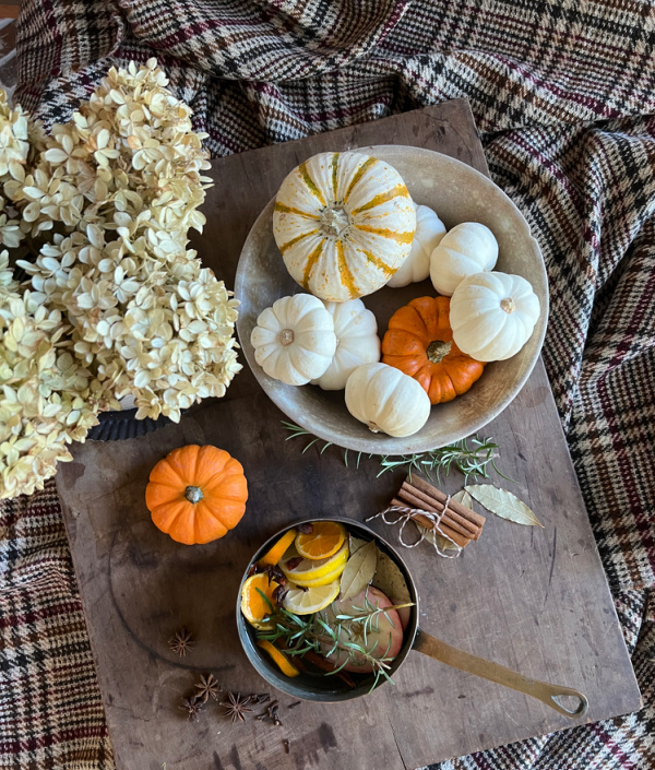 orange and white pumpkins in an ironstone bowl with dried hydrangeas and a copper pot.