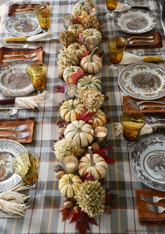 Thanksgiving table with plaid tablecloth and lots of pumpkins. 