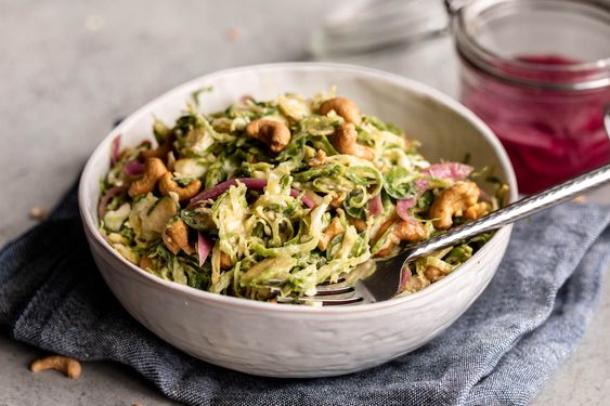 SHREDDED BRUSSELS SPROUTS SALAD WITH MISO DRESSING in a white bowl. 