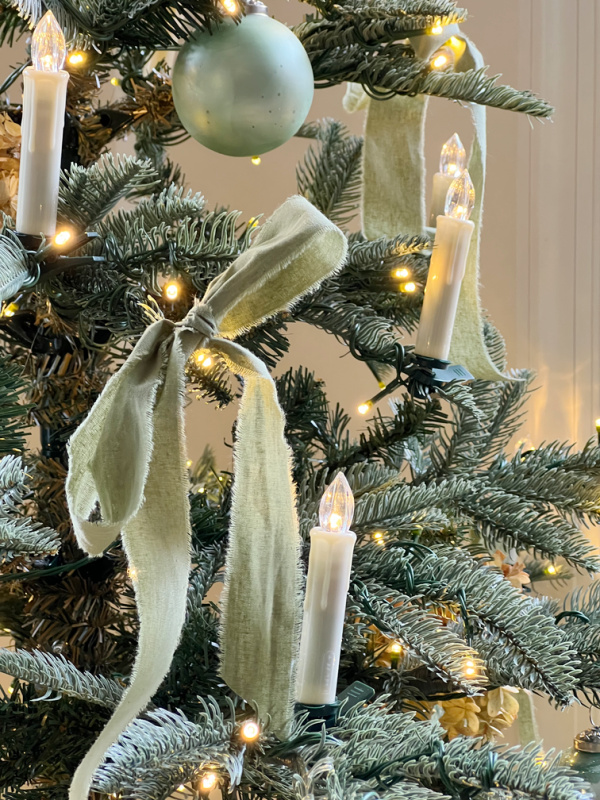 candle lights and a bow on a christmas tree.