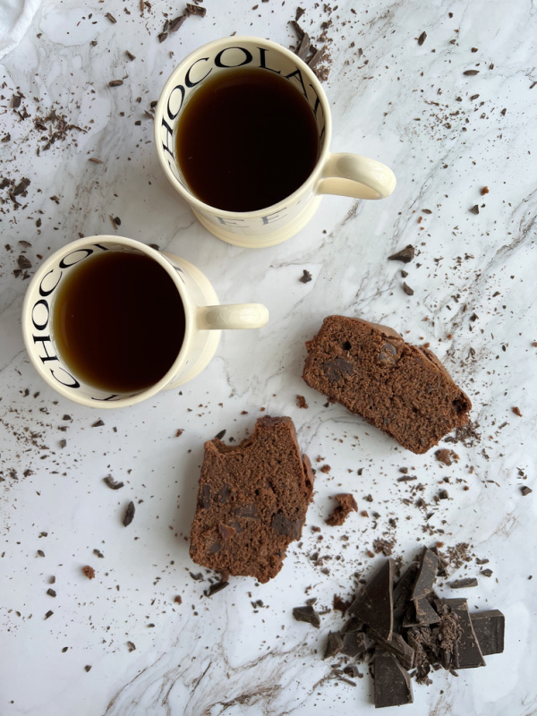 chocolate loaf cake and 2 cups of coffee with a pile of chopped dark chocolate.