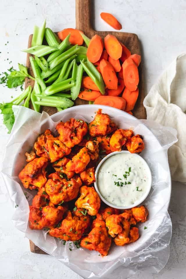 Buffalo Cauliflower in a bowl with carrots and celery on the side. 