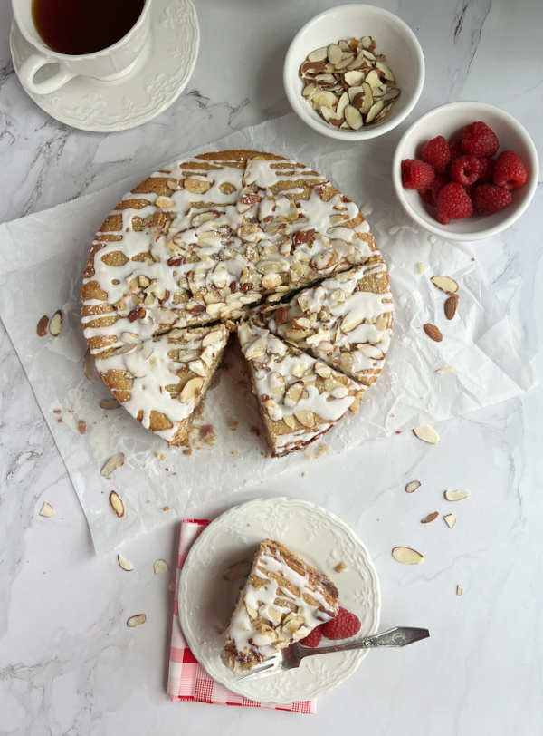 Raspberry Almond coffee cake with raspberries and almonds in white bowls and a cups of tea.