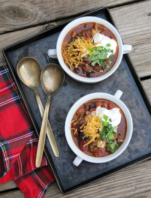 Guinness Chili in 2 white bowls on a pan with two spoons.