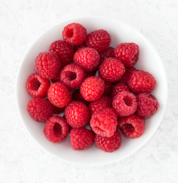 Fresh raspberries in a white bowl.