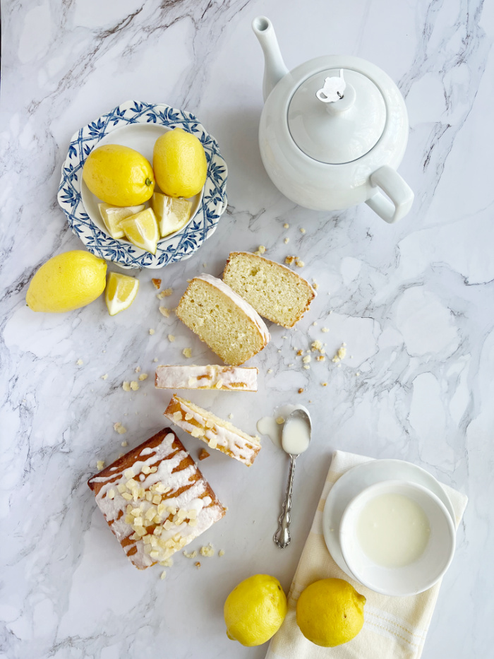 candied lemon pound cake with lemons, a teapot and spoons. 